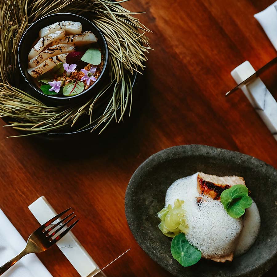 Seared scallops in a black bowl.