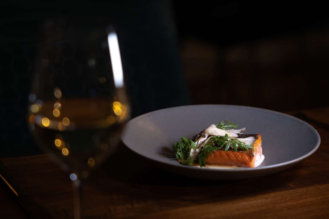 Salmon plate beside a glass of wine.